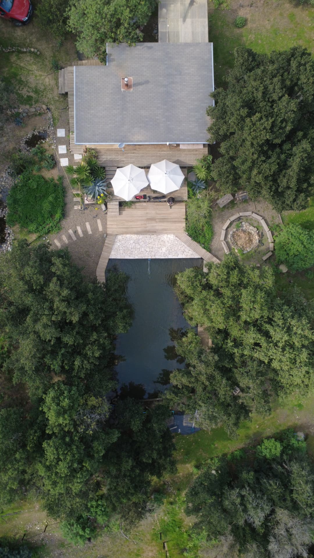 Vista aérea cenital del refugio, la terraza y la biopiscina entre el bosque